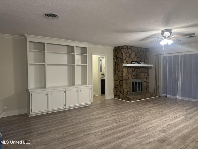 unfurnished living room with crown molding, a textured ceiling, a fireplace, and light hardwood / wood-style flooring