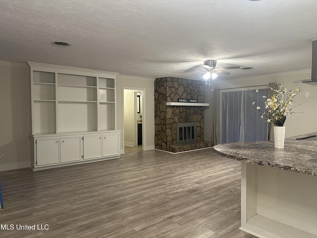 unfurnished living room featuring ornamental molding, a fireplace, hardwood / wood-style floors, and a textured ceiling