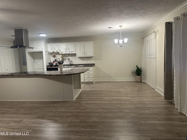 kitchen with pendant lighting, crown molding, dark wood-type flooring, white cabinets, and island exhaust hood