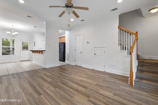 unfurnished living room featuring ceiling fan with notable chandelier, ornamental molding, and hardwood / wood-style floors