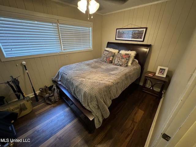 bedroom with wood finished floors, baseboards, wood walls, and ornamental molding