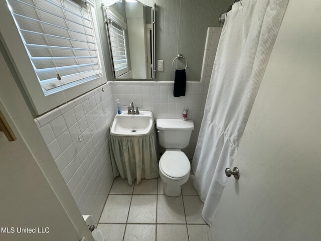 full bath featuring a sink, curtained shower, tile patterned floors, toilet, and tile walls