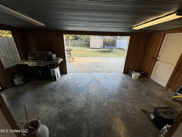 garage featuring a storage shed, a trampoline, and wood walls