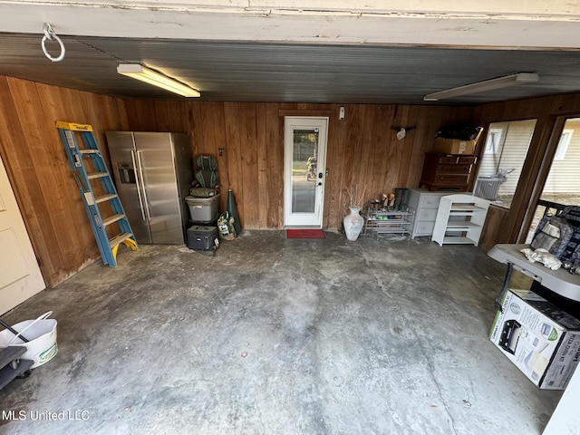 garage with wood walls and stainless steel refrigerator with ice dispenser