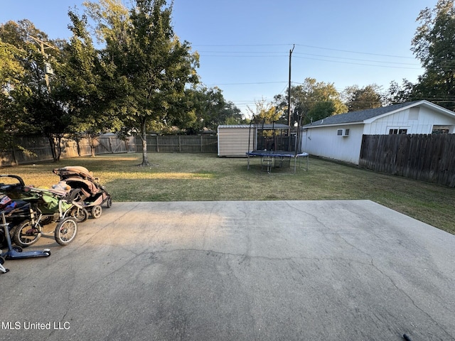 view of yard featuring an outbuilding, a trampoline, a patio, and a fenced backyard