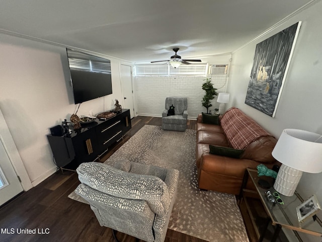 living area with a wall mounted air conditioner, brick wall, dark wood finished floors, and a ceiling fan