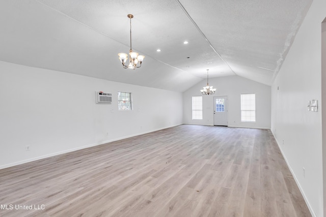 unfurnished living room featuring a chandelier, a textured ceiling, light hardwood / wood-style floors, and lofted ceiling