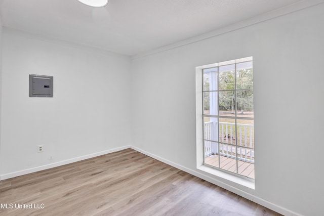 empty room featuring electric panel, crown molding, and light hardwood / wood-style floors