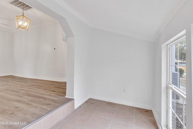 unfurnished room with light tile patterned floors, crown molding, and an inviting chandelier