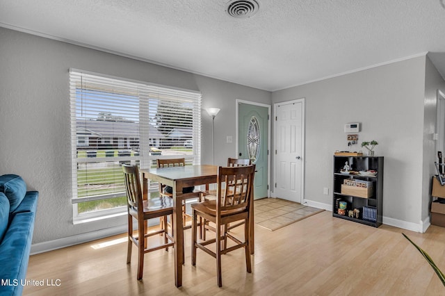 dining space with ornamental molding, a textured ceiling, and wood-type flooring