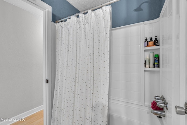 bathroom featuring shower / bath combination with curtain, hardwood / wood-style flooring, and a textured ceiling