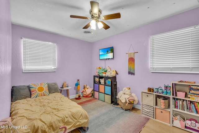 bedroom featuring light hardwood / wood-style flooring, multiple windows, and ceiling fan