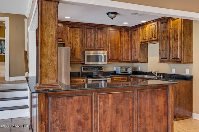 kitchen featuring kitchen peninsula, stainless steel appliances, dark stone counters, and sink