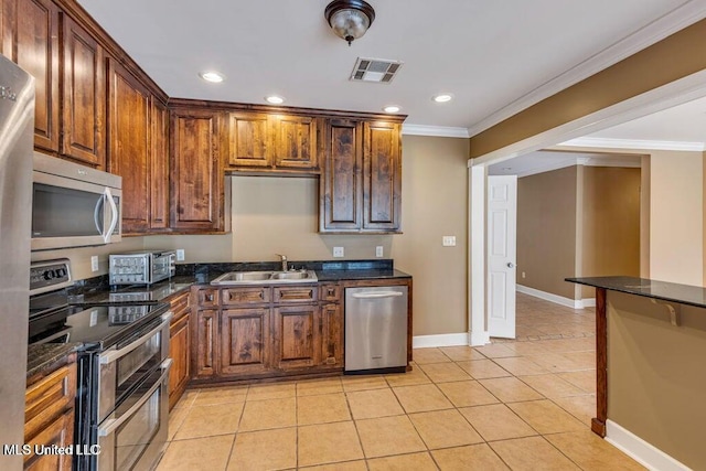 kitchen with sink, appliances with stainless steel finishes, dark stone counters, light tile patterned floors, and ornamental molding