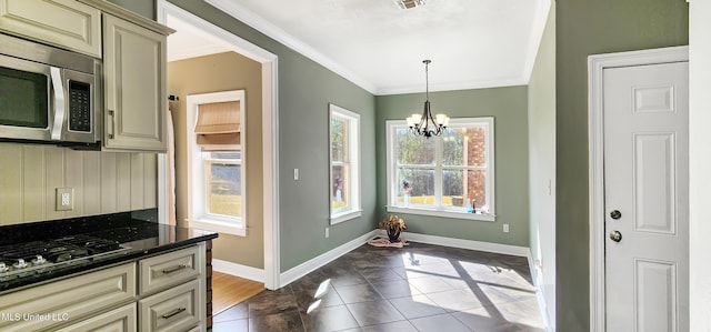 kitchen with crown molding, cream cabinets, decorative light fixtures, dark tile patterned flooring, and a notable chandelier