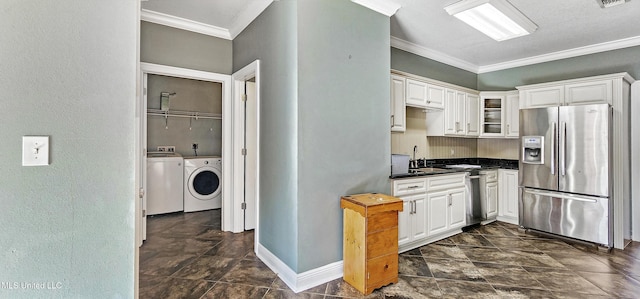 kitchen with washing machine and clothes dryer, white cabinets, ornamental molding, and appliances with stainless steel finishes