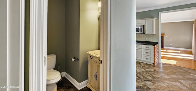 bathroom with decorative backsplash, crown molding, vanity, and toilet