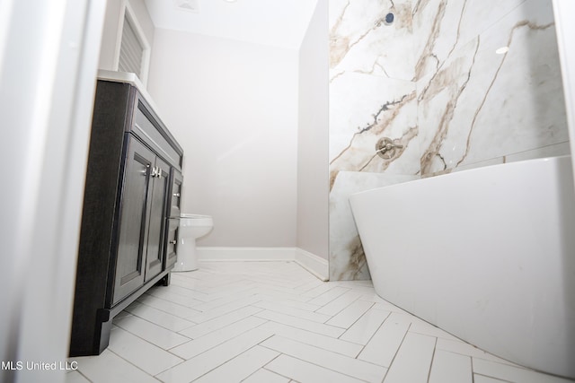 bathroom with a freestanding tub, baseboards, and toilet