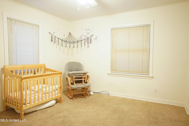 carpeted bedroom featuring a crib and ceiling fan