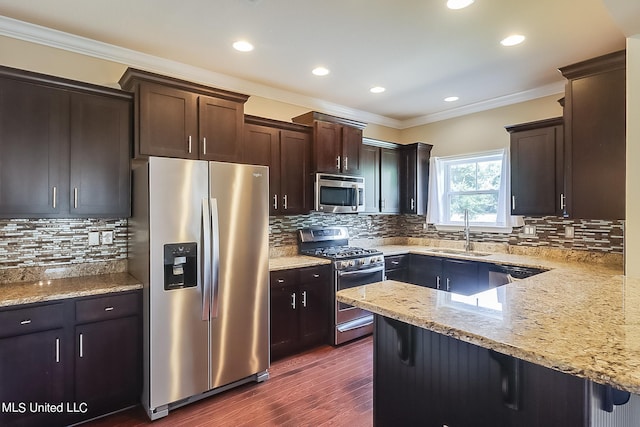 kitchen with tasteful backsplash, appliances with stainless steel finishes, sink, a breakfast bar, and dark hardwood / wood-style floors