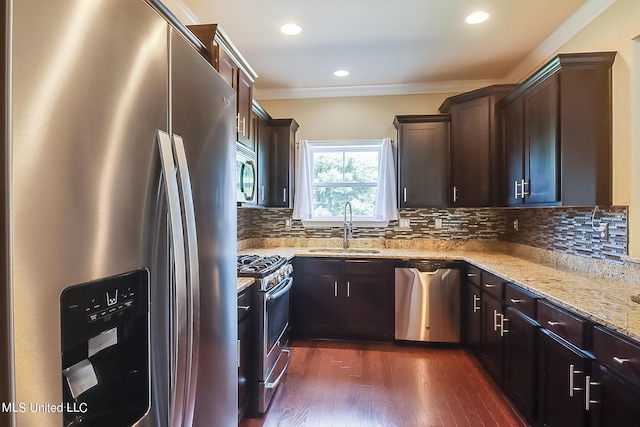 kitchen with stainless steel appliances, ornamental molding, sink, light stone counters, and dark hardwood / wood-style flooring