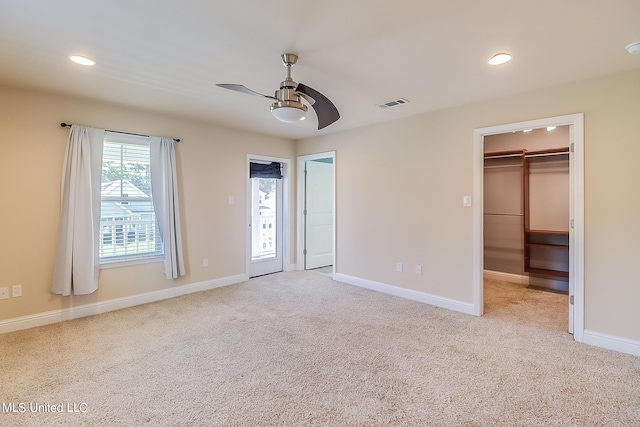 unfurnished bedroom with a spacious closet, ceiling fan, a closet, and light colored carpet