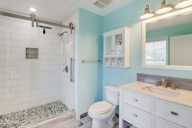 bathroom featuring vanity, toilet, a shower with door, and hardwood / wood-style floors