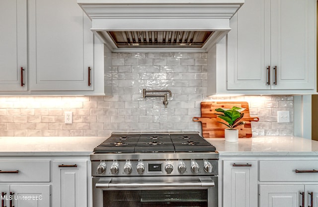 kitchen with decorative backsplash, high end stove, white cabinetry, and custom exhaust hood