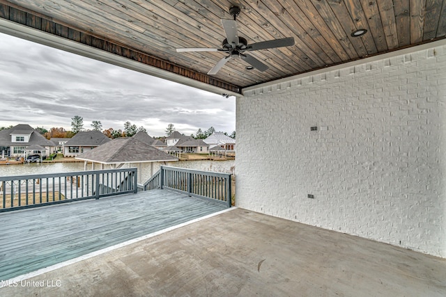 wooden terrace with a water view and ceiling fan