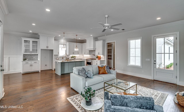 living room with ceiling fan, sink, dark hardwood / wood-style floors, and ornamental molding