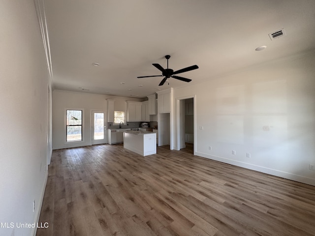 unfurnished living room featuring sink, crown molding, light hardwood / wood-style floors, and ceiling fan