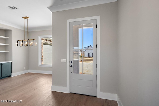 doorway to outside with light hardwood / wood-style floors, crown molding, and a chandelier