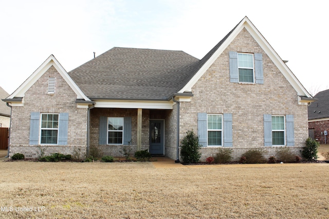 craftsman-style house with brick siding, a front lawn, and roof with shingles