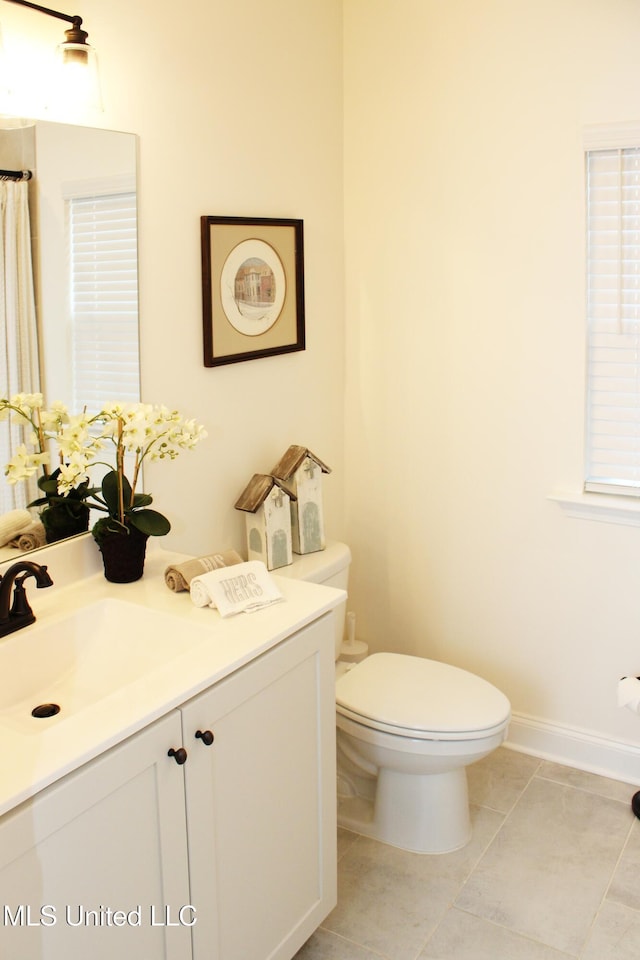 bathroom featuring tile patterned flooring, vanity, toilet, and baseboards