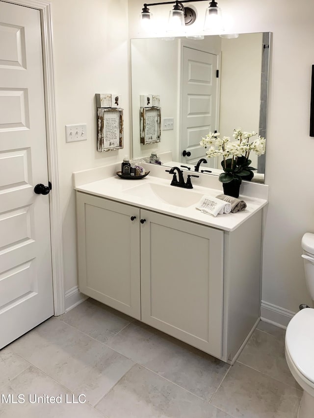 bathroom featuring vanity, toilet, and baseboards