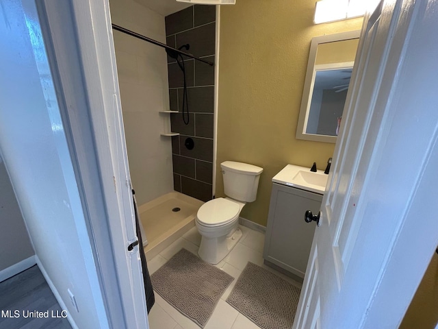 bathroom featuring toilet, a shower stall, vanity, tile patterned flooring, and baseboards