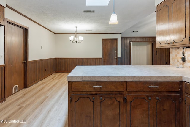 504 Hampton St, Clinton, MS 39056 - kitchen featuring a wainscoted wall, a peninsula, light wood-type flooring, ornamental molding, and light countertops