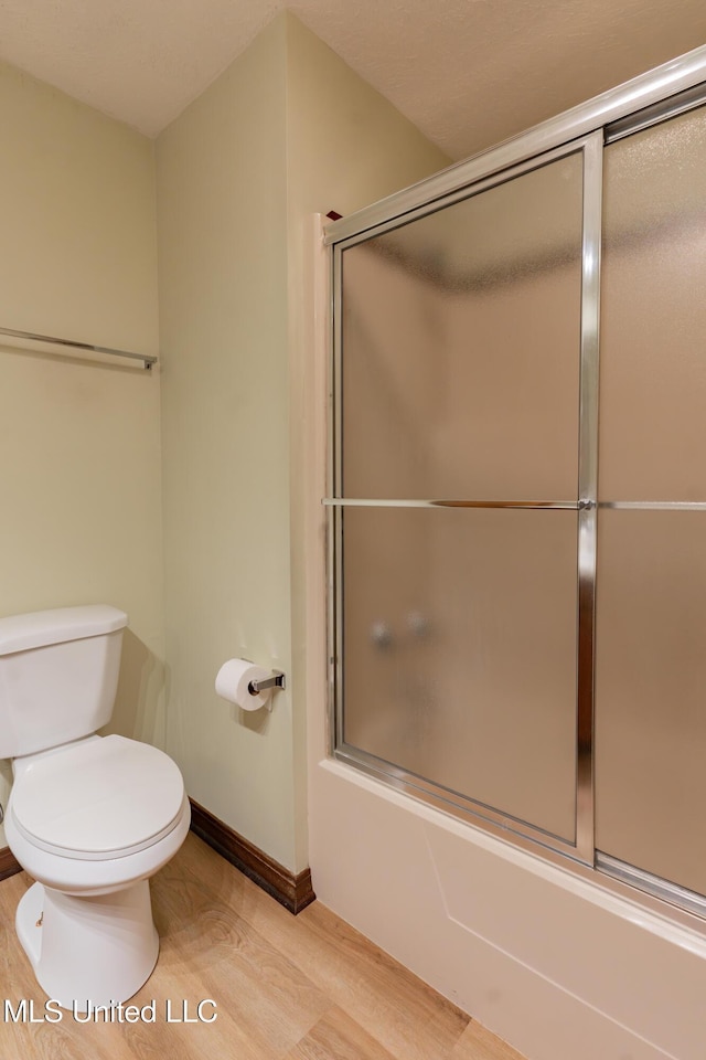 504 Hampton St, Clinton, MS 39056 - bathroom with wood finished floors, enclosed tub / shower combo, toilet, and baseboards