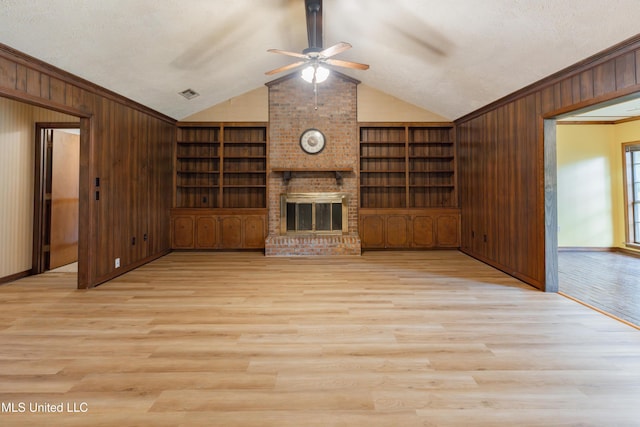 504 Hampton St, Clinton, MS 39056 - unfurnished living room with wooden walls, ceiling fan, lofted ceiling, wood finished floors, and a fireplace