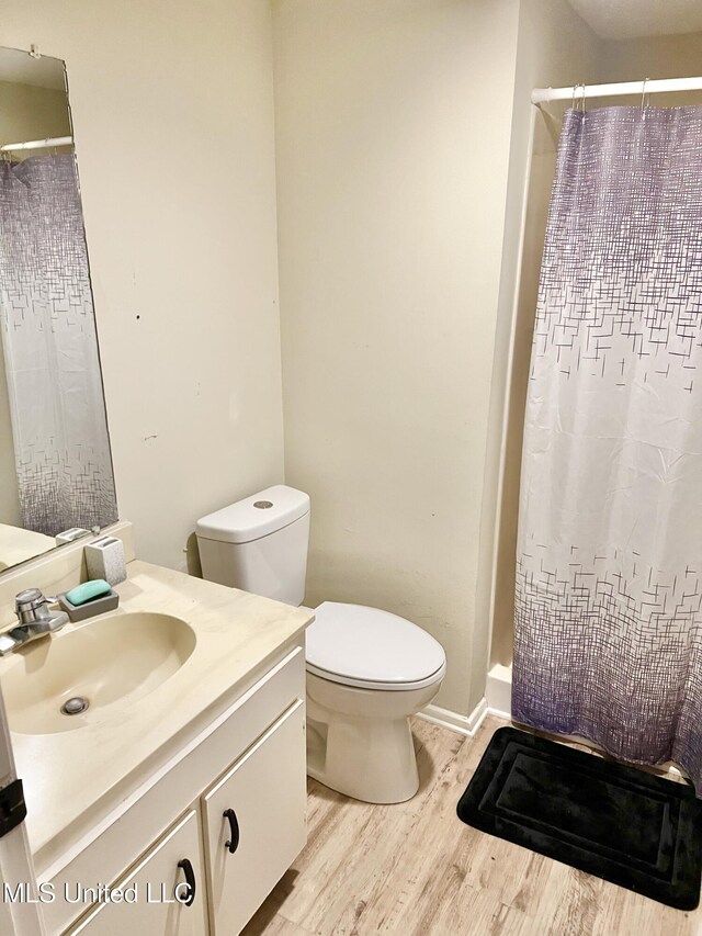 bathroom with hardwood / wood-style flooring, vanity, toilet, and walk in shower