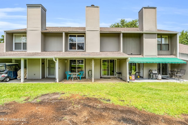 257 Highpoint Dr Unit 257, Diamondhead, MS 39525 - rear view of house with a chimney, a shingled roof, a yard, and a patio