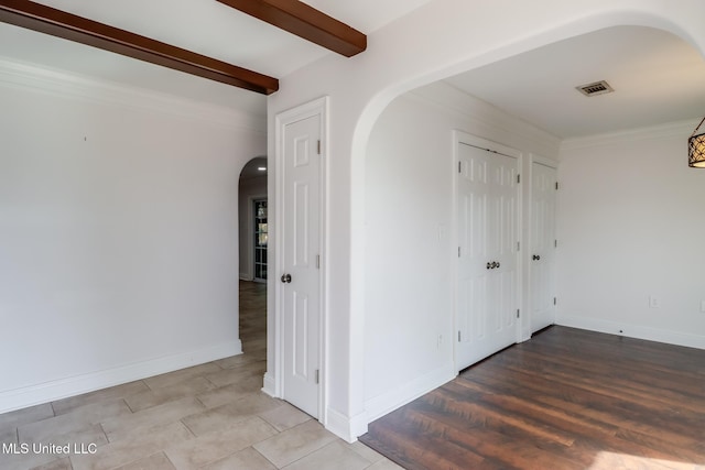 empty room featuring crown molding, wood-type flooring, and beamed ceiling