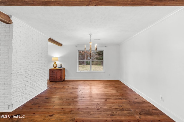 spare room featuring ornamental molding, brick wall, dark hardwood / wood-style floors, and an inviting chandelier