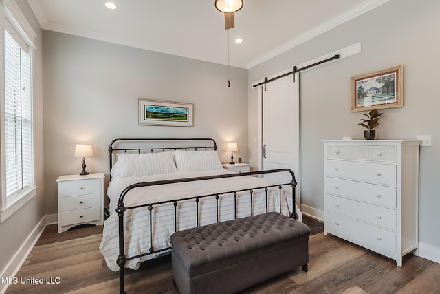 bedroom featuring crown molding, a barn door, dark wood-type flooring, and multiple windows