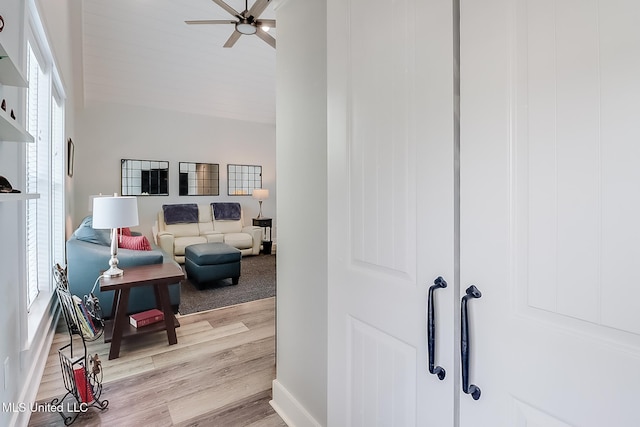 corridor with lofted ceiling and light hardwood / wood-style floors