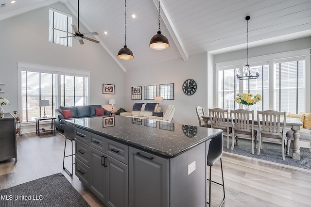 kitchen with dark stone countertops, hanging light fixtures, a kitchen island, and a kitchen bar