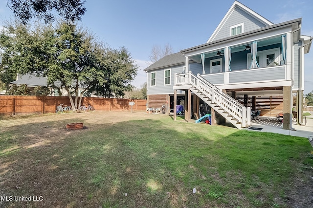 back of house with a lawn, ceiling fan, and an outdoor fire pit