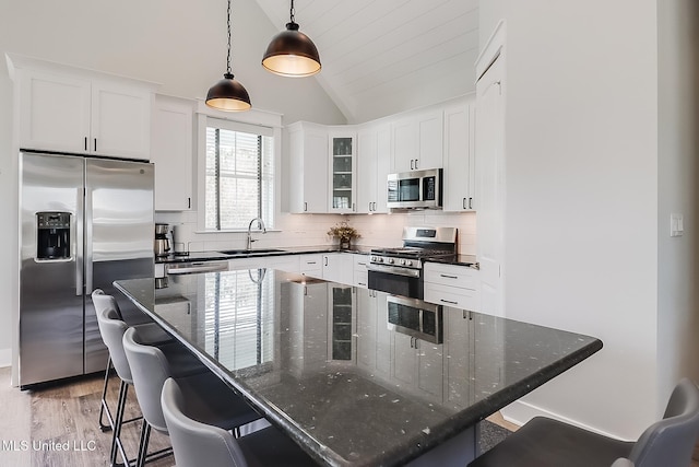 kitchen with pendant lighting, a breakfast bar, white cabinets, and appliances with stainless steel finishes