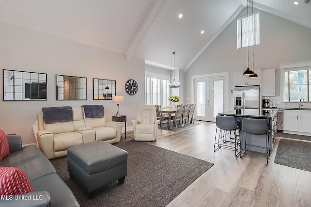 living room featuring sink, light hardwood / wood-style flooring, high vaulted ceiling, french doors, and beamed ceiling