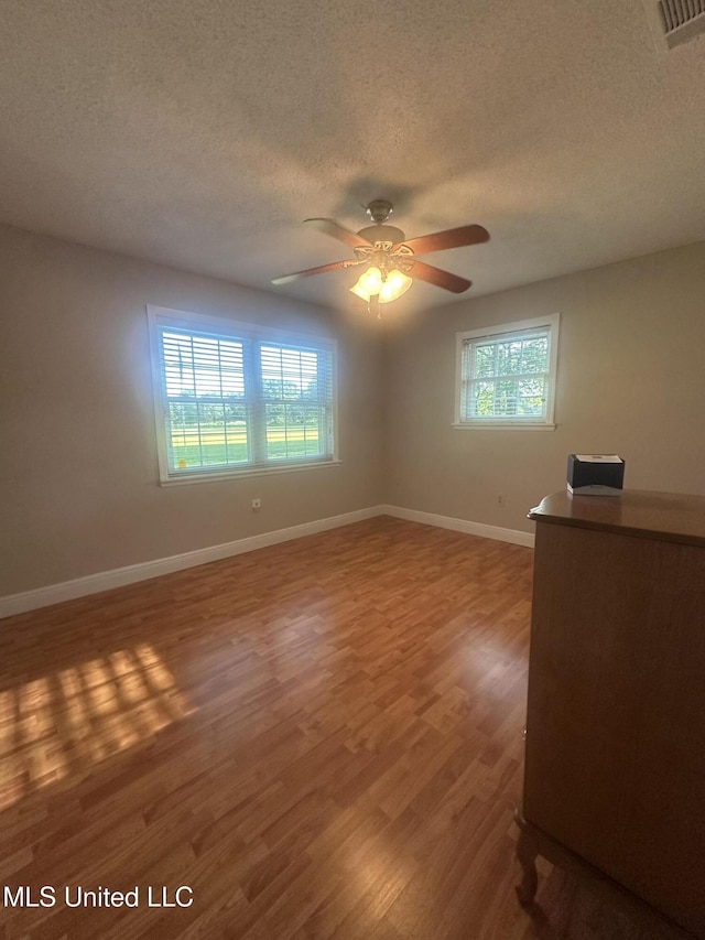 6709 Caraway Rd, Moss Point, MS 39562 - spare room with a textured ceiling, a ceiling fan, a healthy amount of sunlight, and wood finished floors
